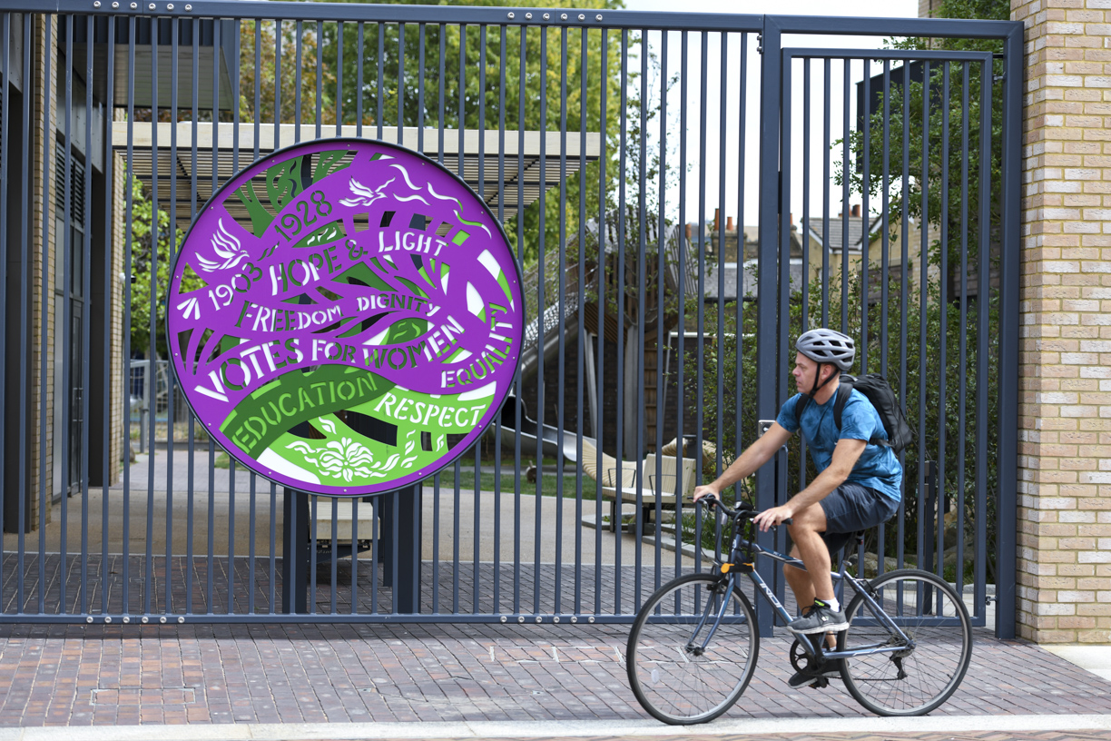 A cyclist passing the Votes for Women artwork